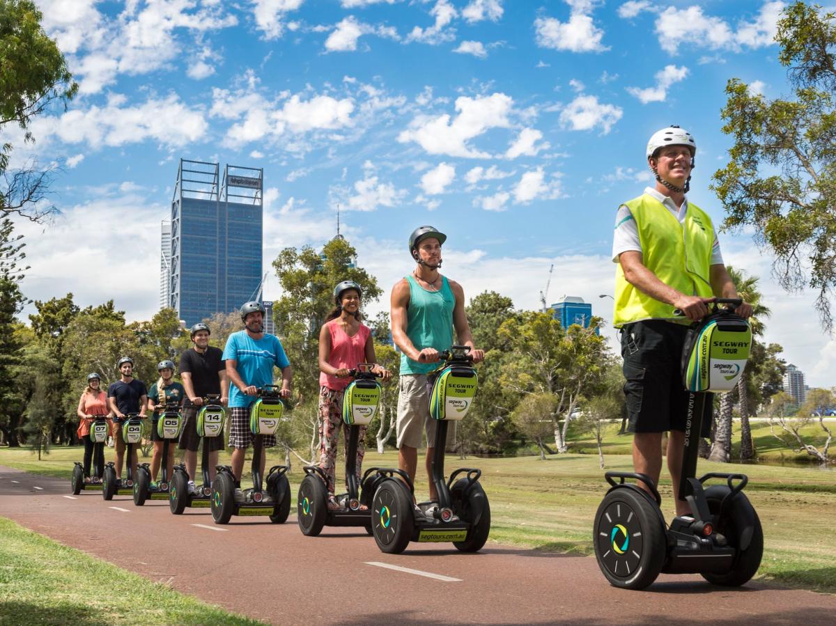 Group segway tour cruising along the path, with the city skyline in the background.