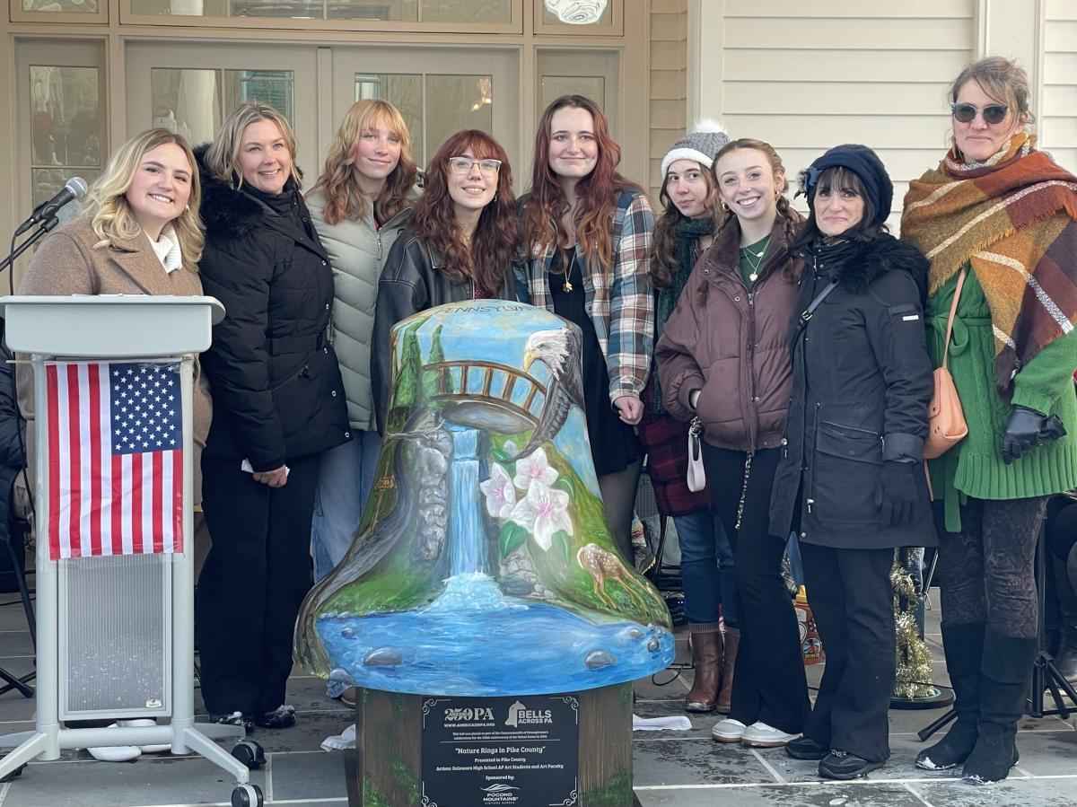 Group stands next to the Pike County America250PA bell in Milford, PA.