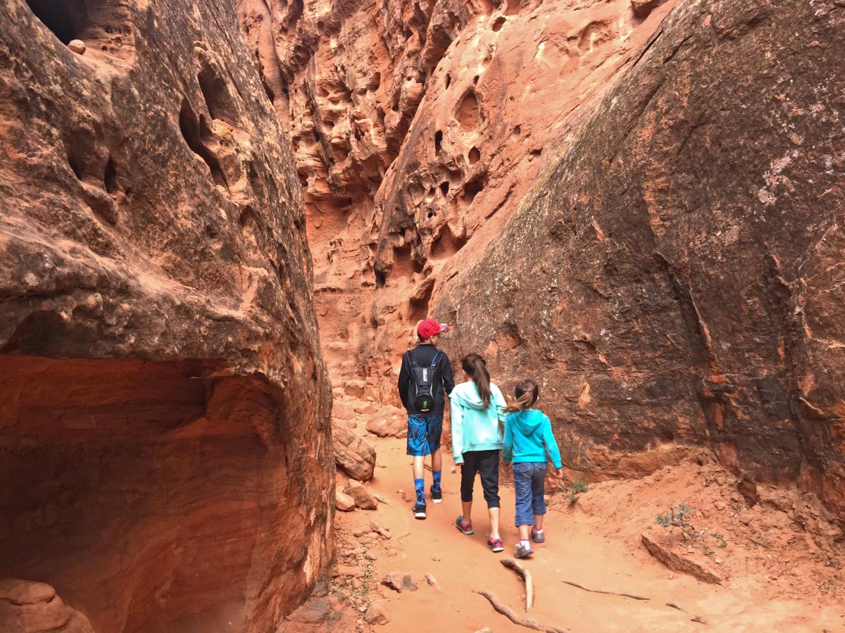 Three kids hiking through red rocks in Southern Utah in Snow Canyon