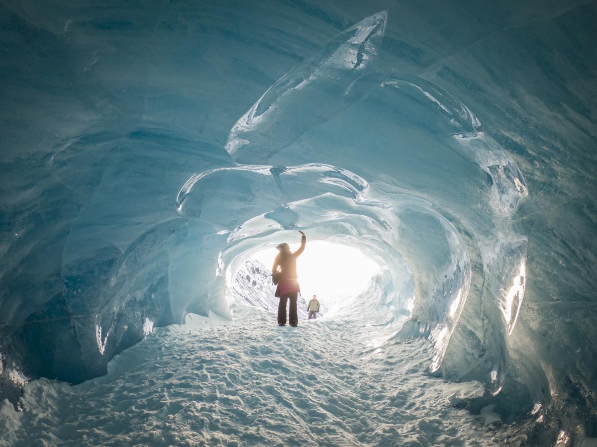 a person stands in an ice cave touching the icy walls