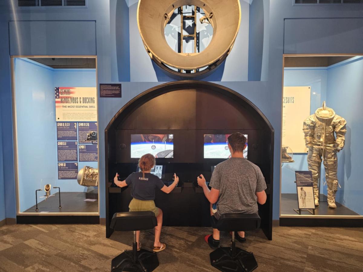 A young man and girl play with a flight simulator at the Cosmosphere science museum.