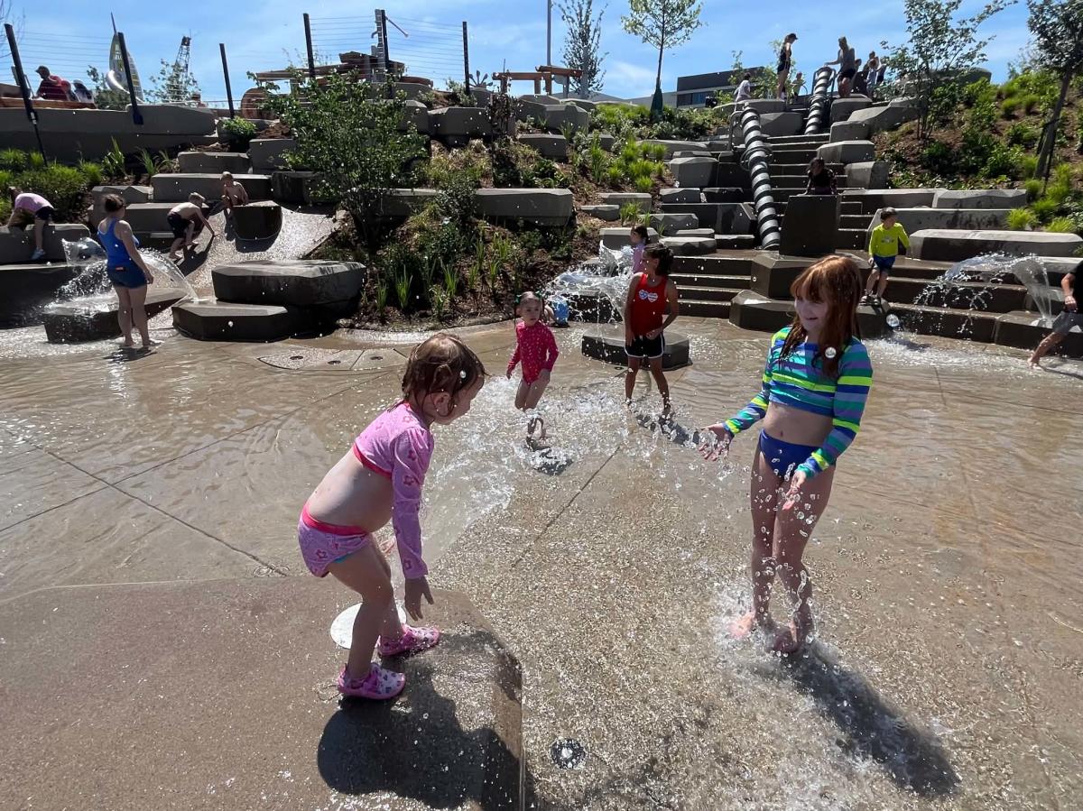 Two young girls play in the water at Water Play Cascades at the Adventure Playscape at Exploration Place.