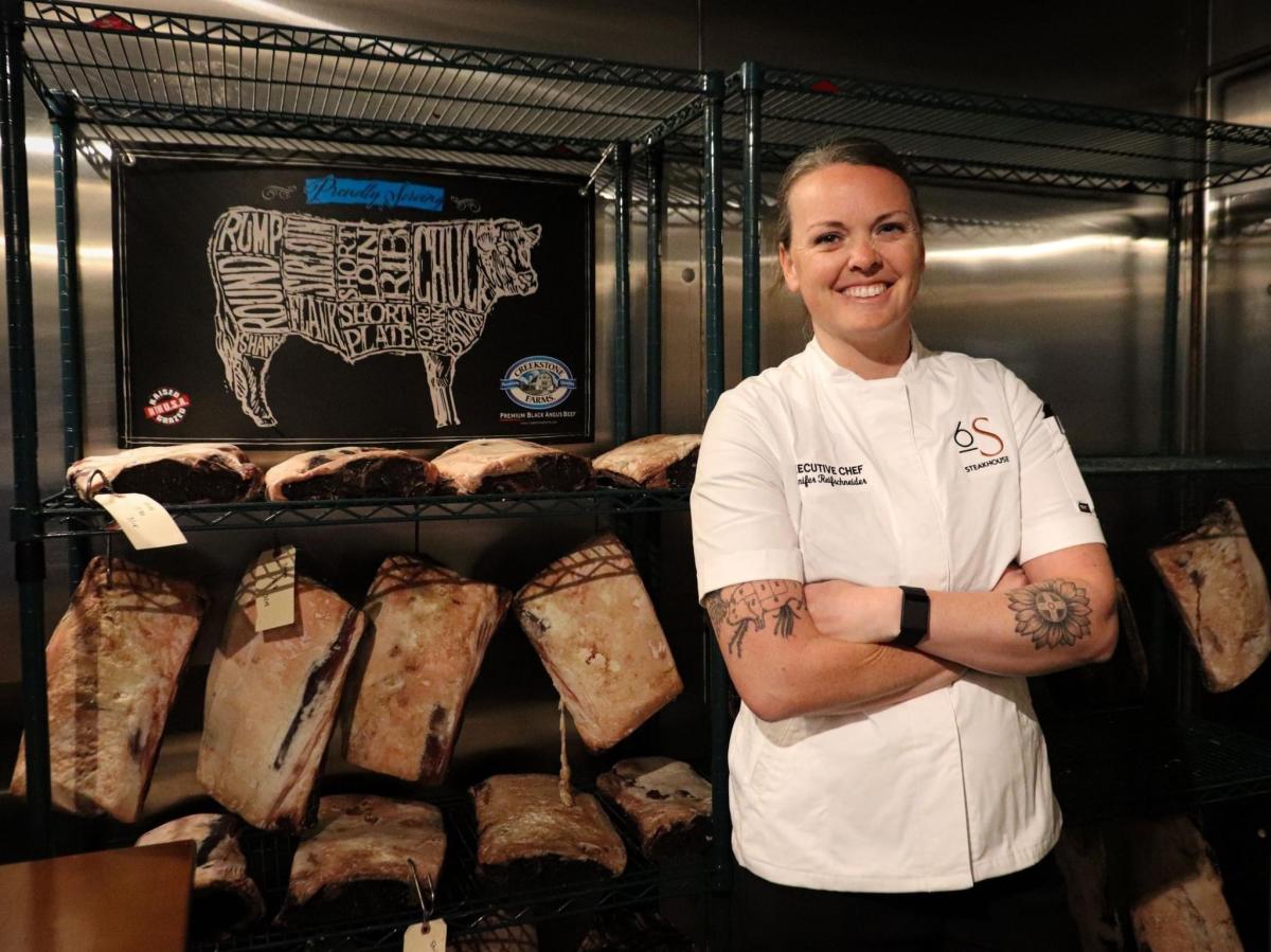 Jennifer Reifschneider, executive chef at 6S Steakhouse, poses in front of beef in the kitchen