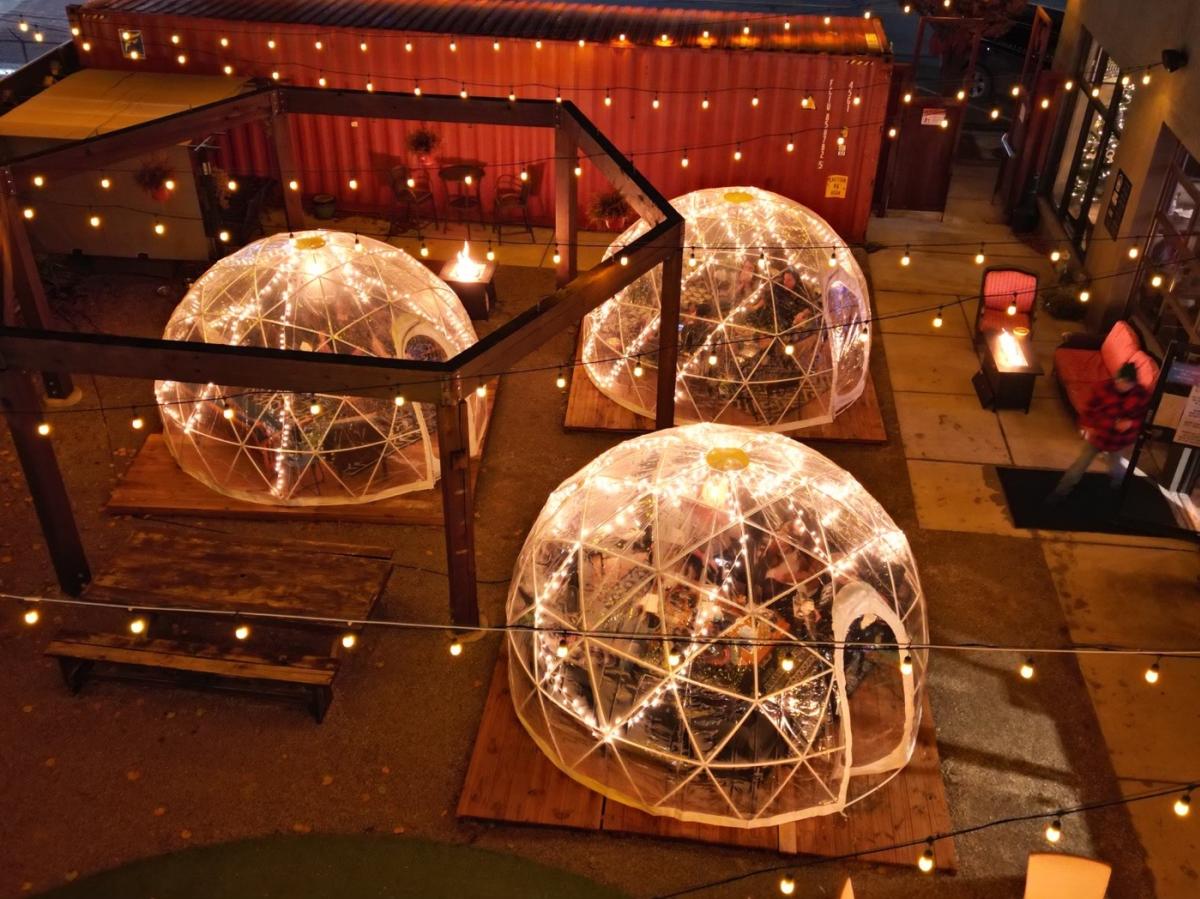 People dine and drink inside igloos on the patio at Nortons