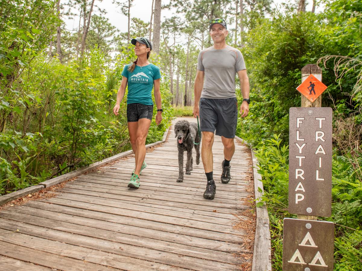Couple walking with dog at Carolina Beach State Park on Flytrap Trail
