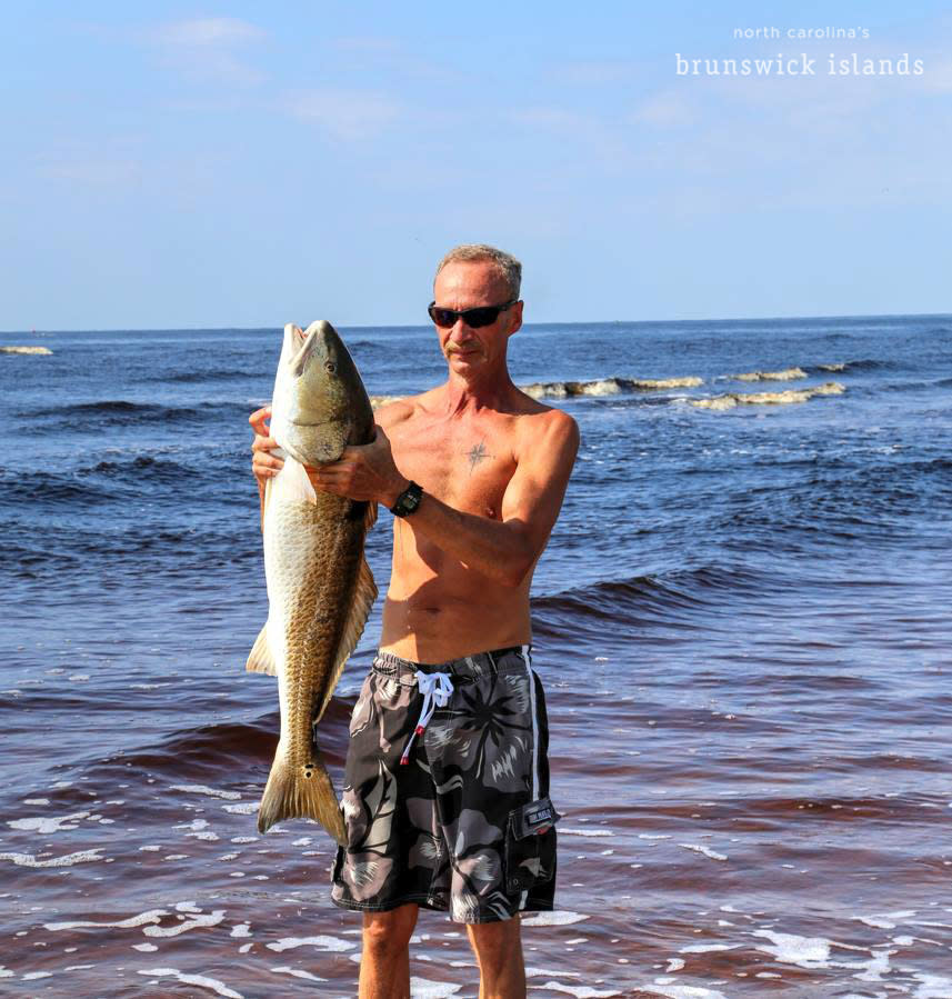 Man holding fish in the surf
