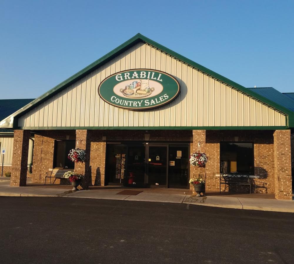 Exterior of the Grabill Country Sales building with a wide doorway and green sign above.
