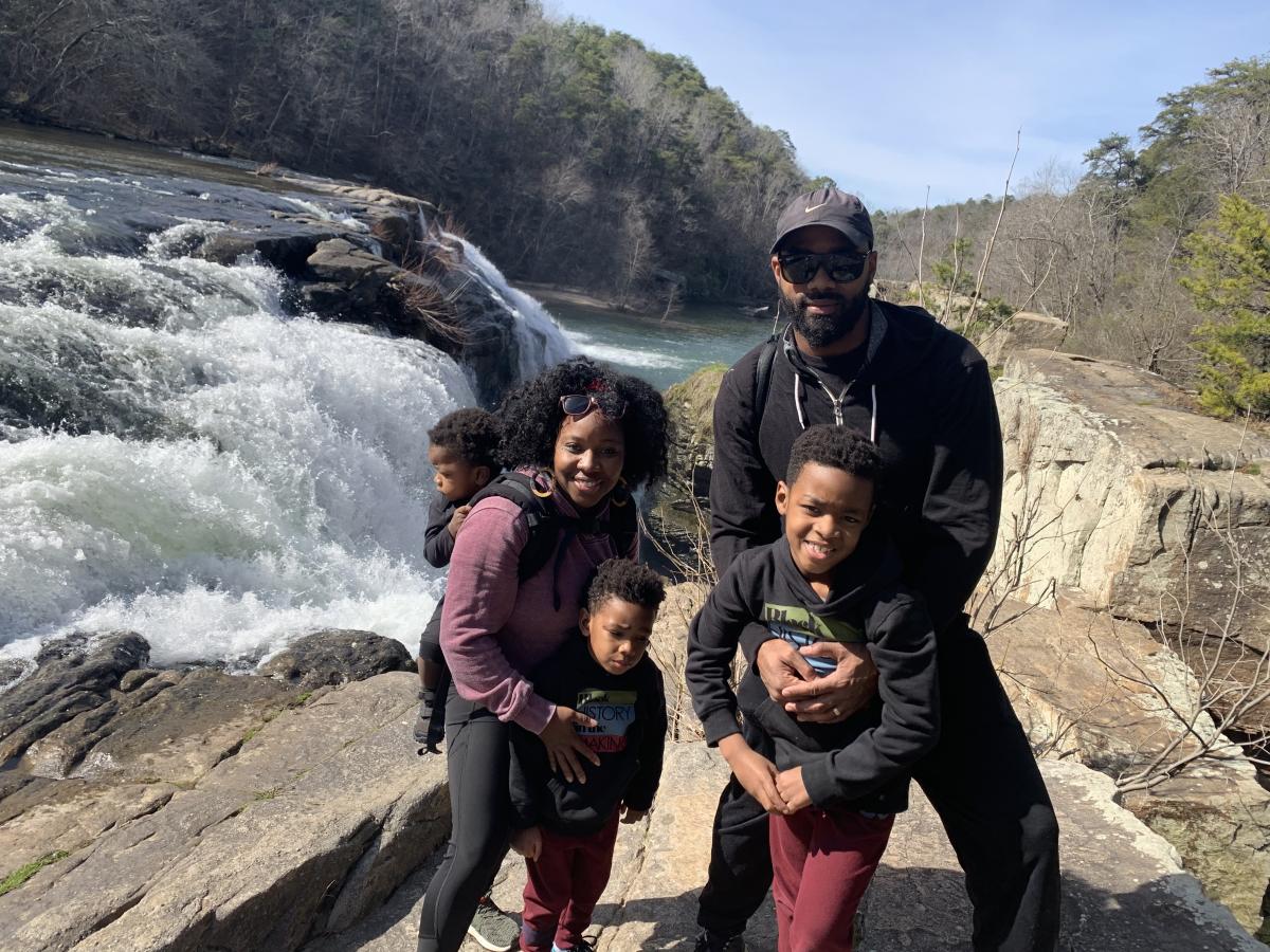 A man, woman and three children pose for a photo with a small waterfall behind them