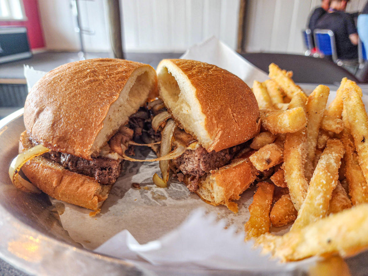 Cheesy burger with sauteed onions and fries on the side.