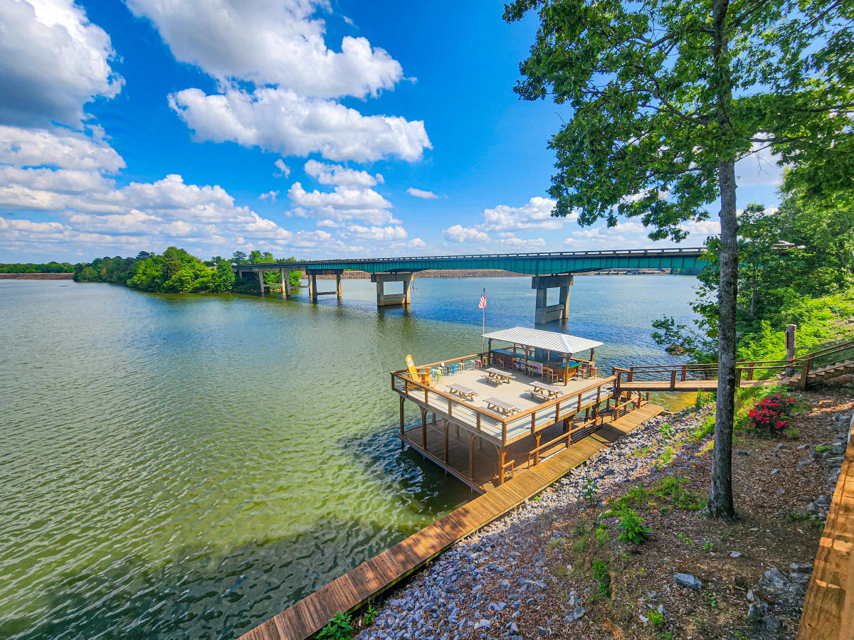 Bridge over Weiss Lake against a blue sky with puffy white clouds. There is a dock in the foreground.