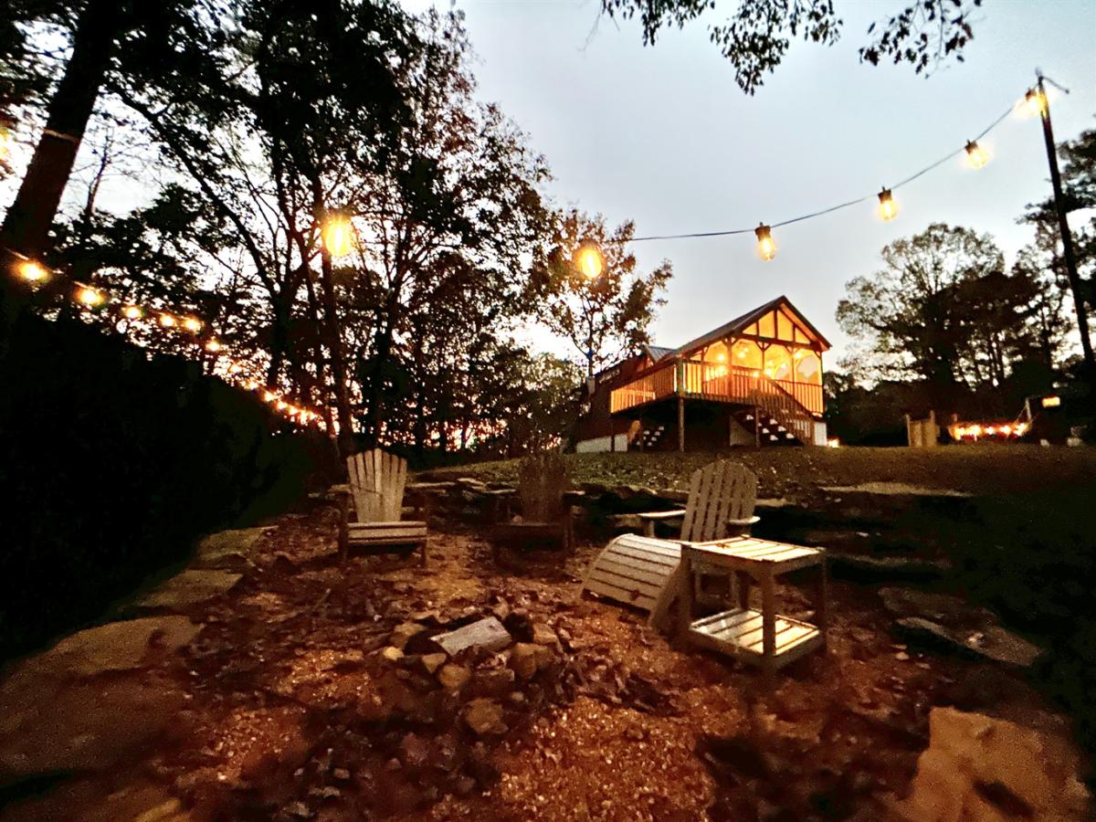 Fire Tower Camp cabin and chairs with string lights at dusk.