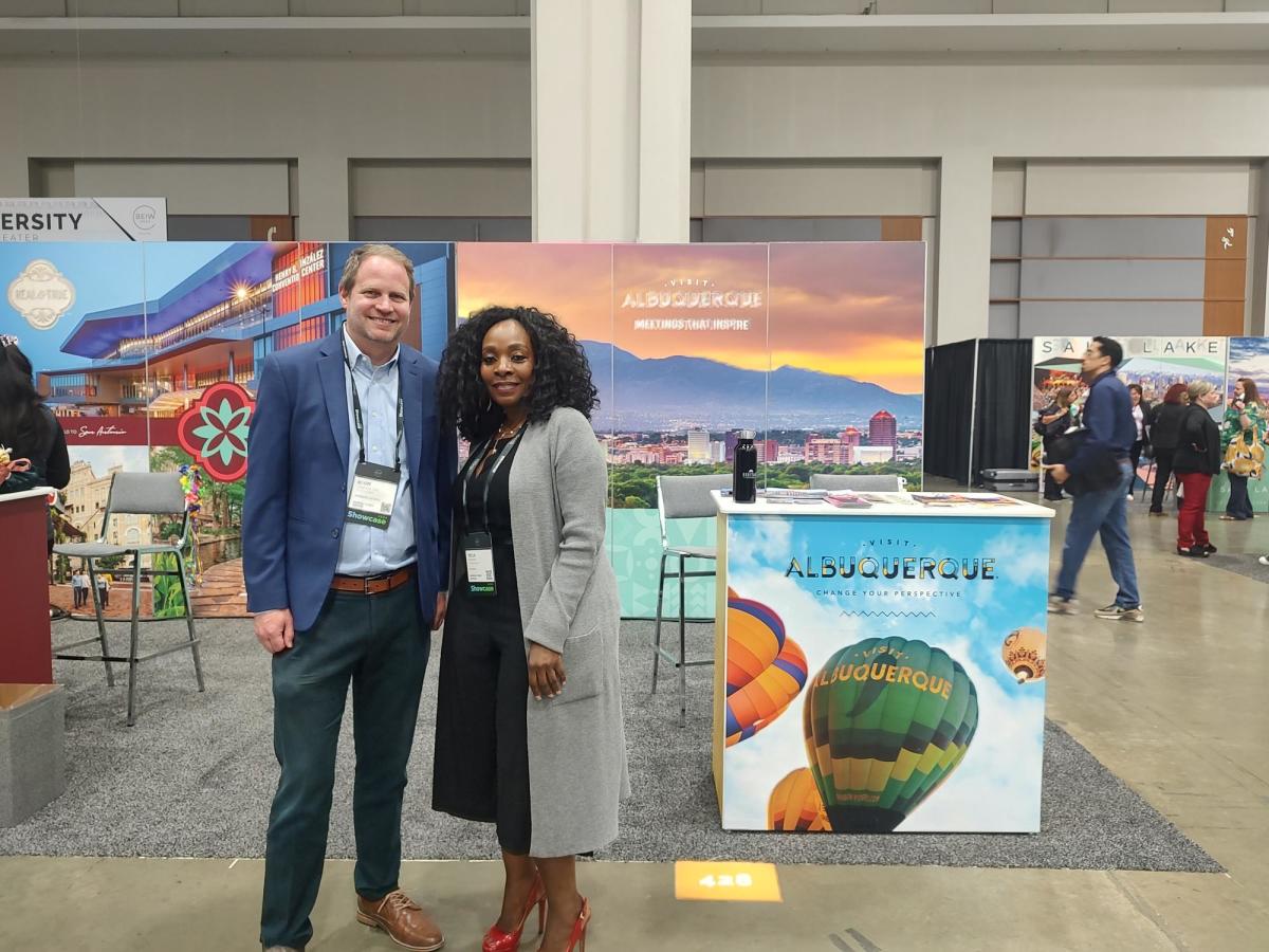 Scott Craighead and Tecla Tawonezvi stand in front of Visit Albuquerque's booth at PCMA Showcase