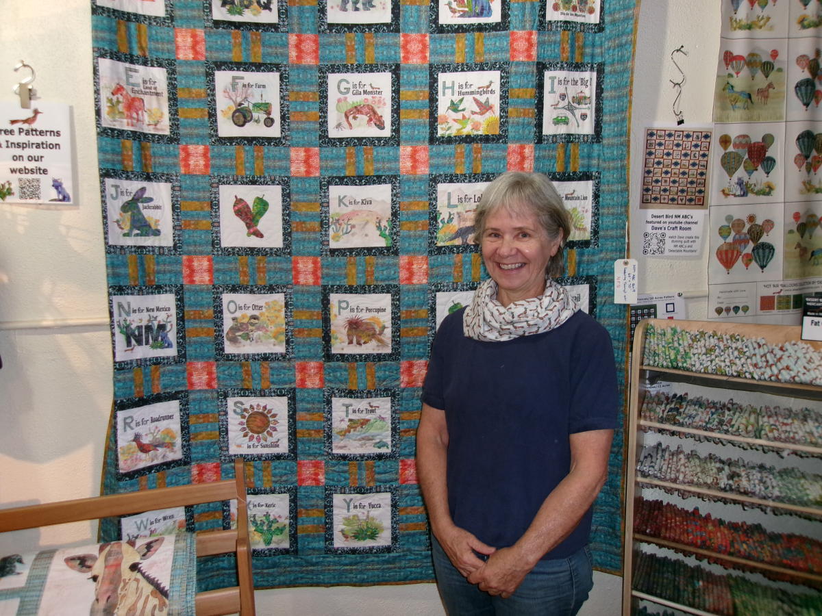 Tammy Wenderlich stands in front of an ABC quilt she designed at Desert Bird Mercantile.