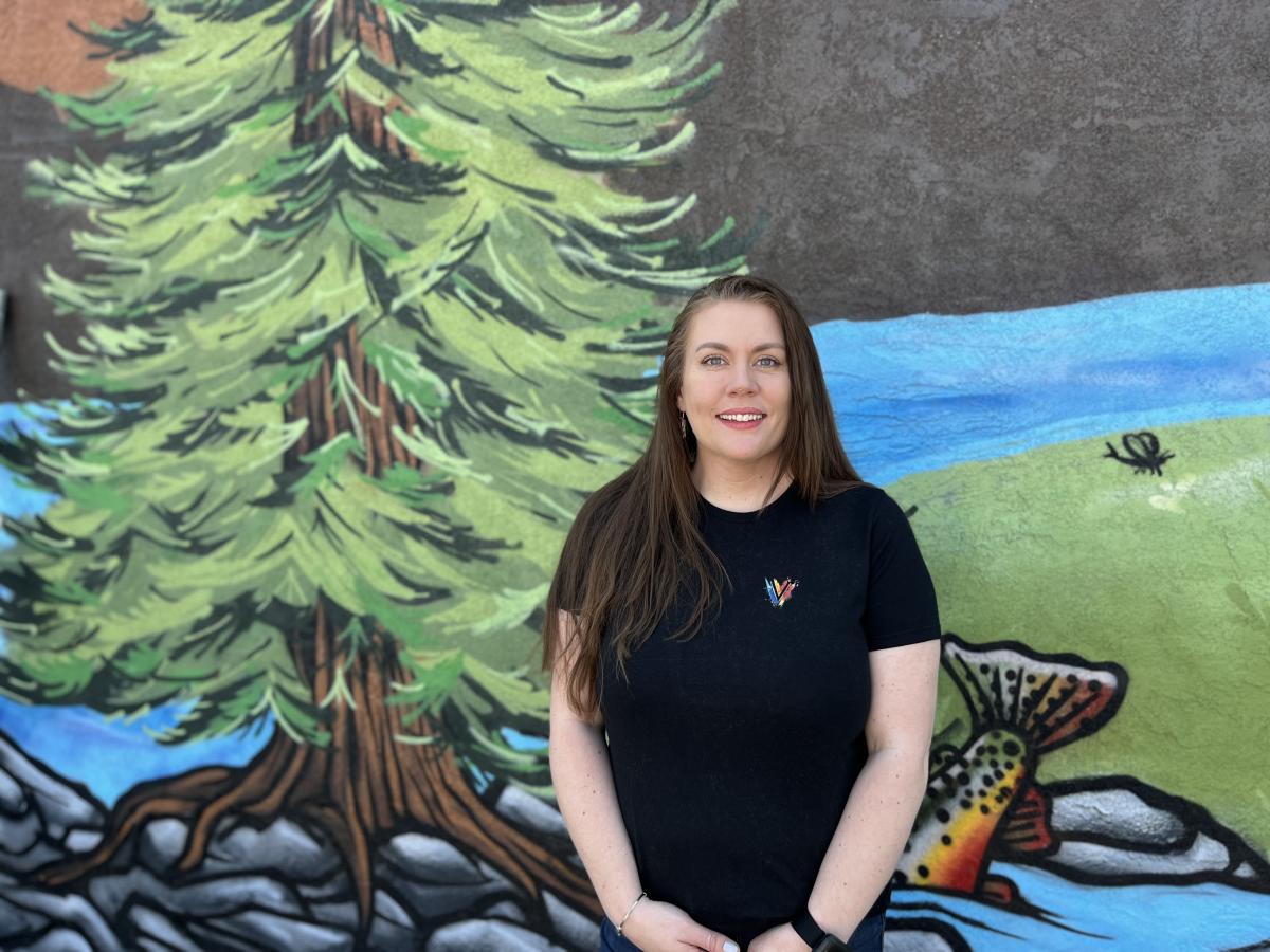 An image of Kat Bloom in front of the mural at Vault Studios.
