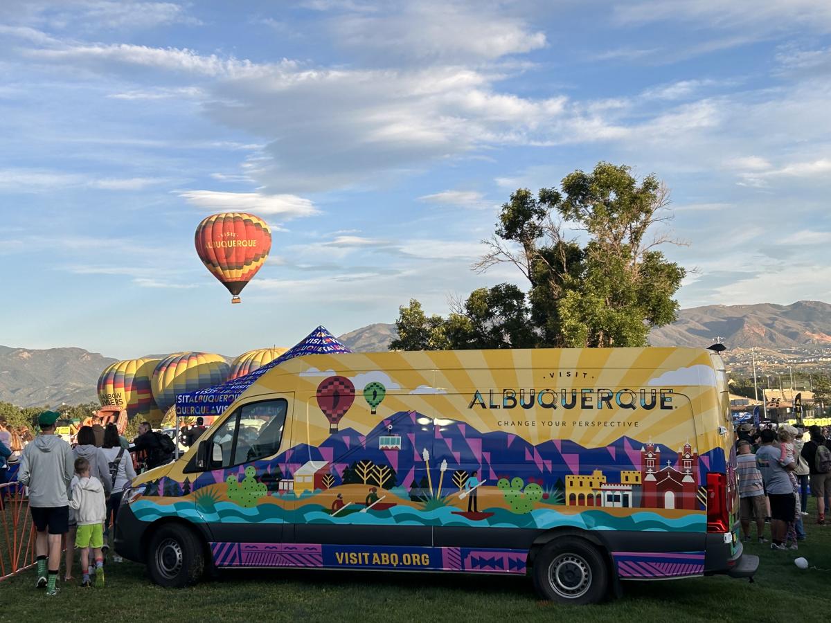 The Visit Albuquerque mobile visitors center in the foreground with the Visit Albuquerque balloon in the background at Labor Day Liftoff