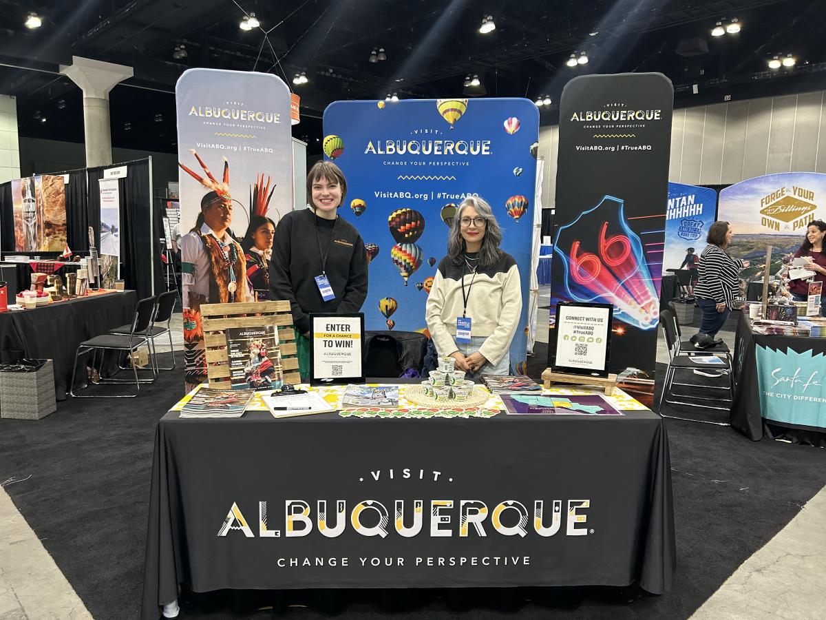 Two Visit Albuquerque employees stand behind the Visit Albuquerque booth at the Los Angeles Travel and Adventure show