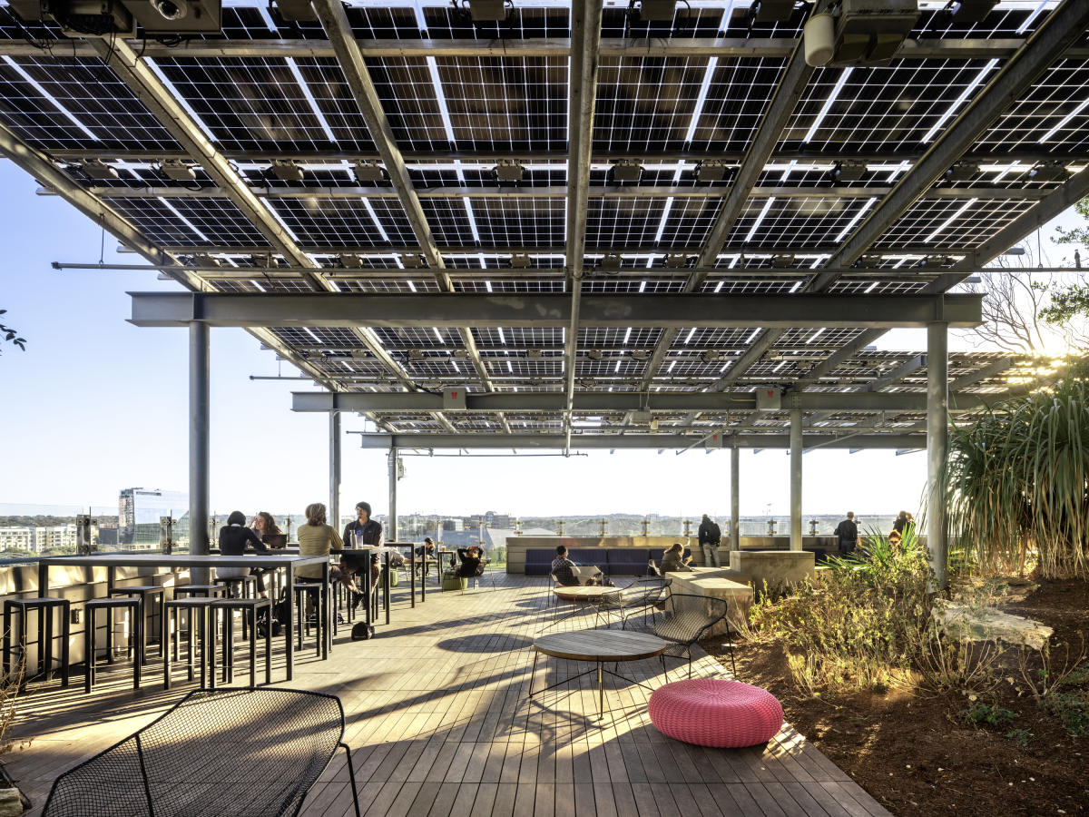 Image of people reading at tables on the rooftop deck of the Austin Central Library in Downtown Austin.