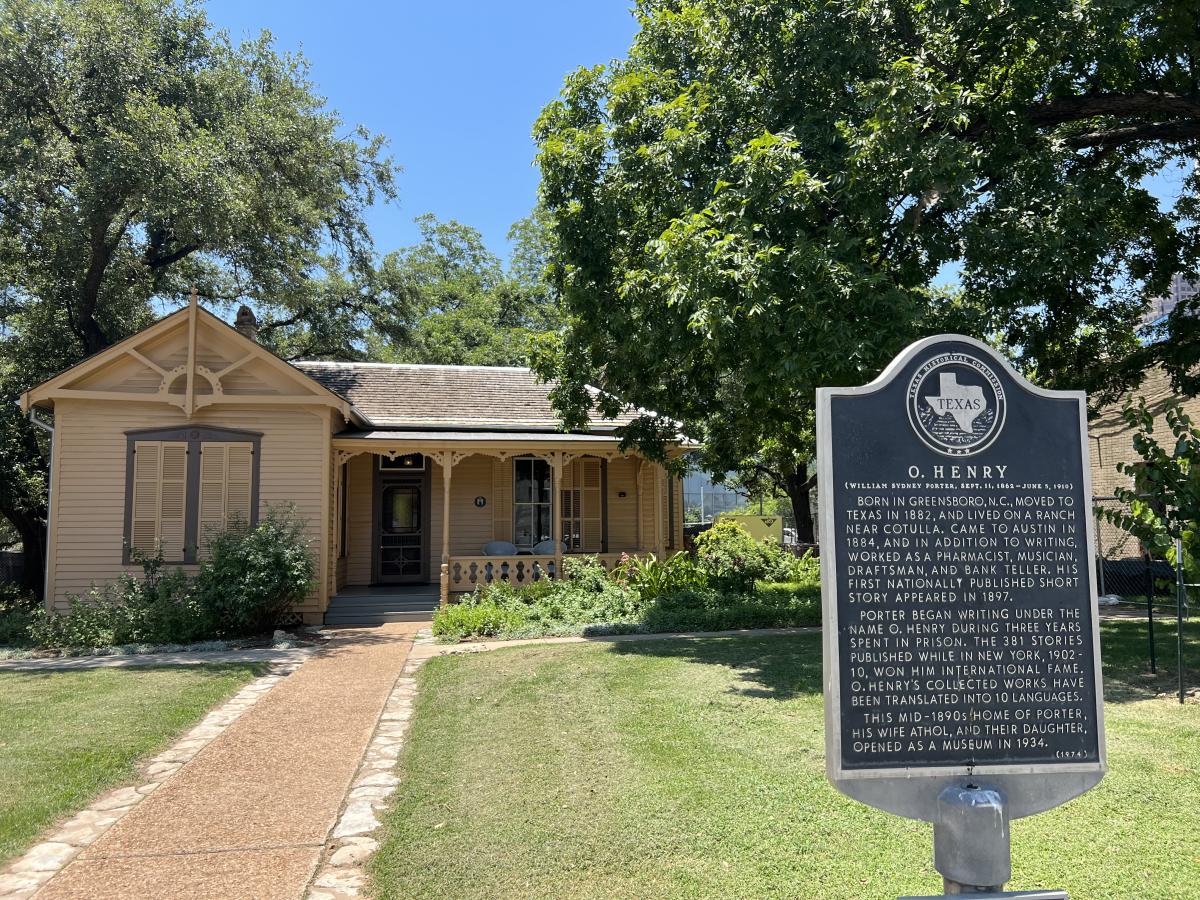 Photo of the exterior of the O. Henry Museum featuring the historical marker posted out front of the house.