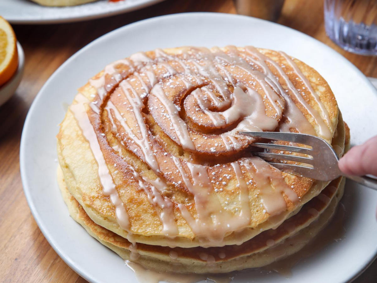 Image of a fork cutting into cinnamon roll pancakes at Kerbey Lane Cafe.