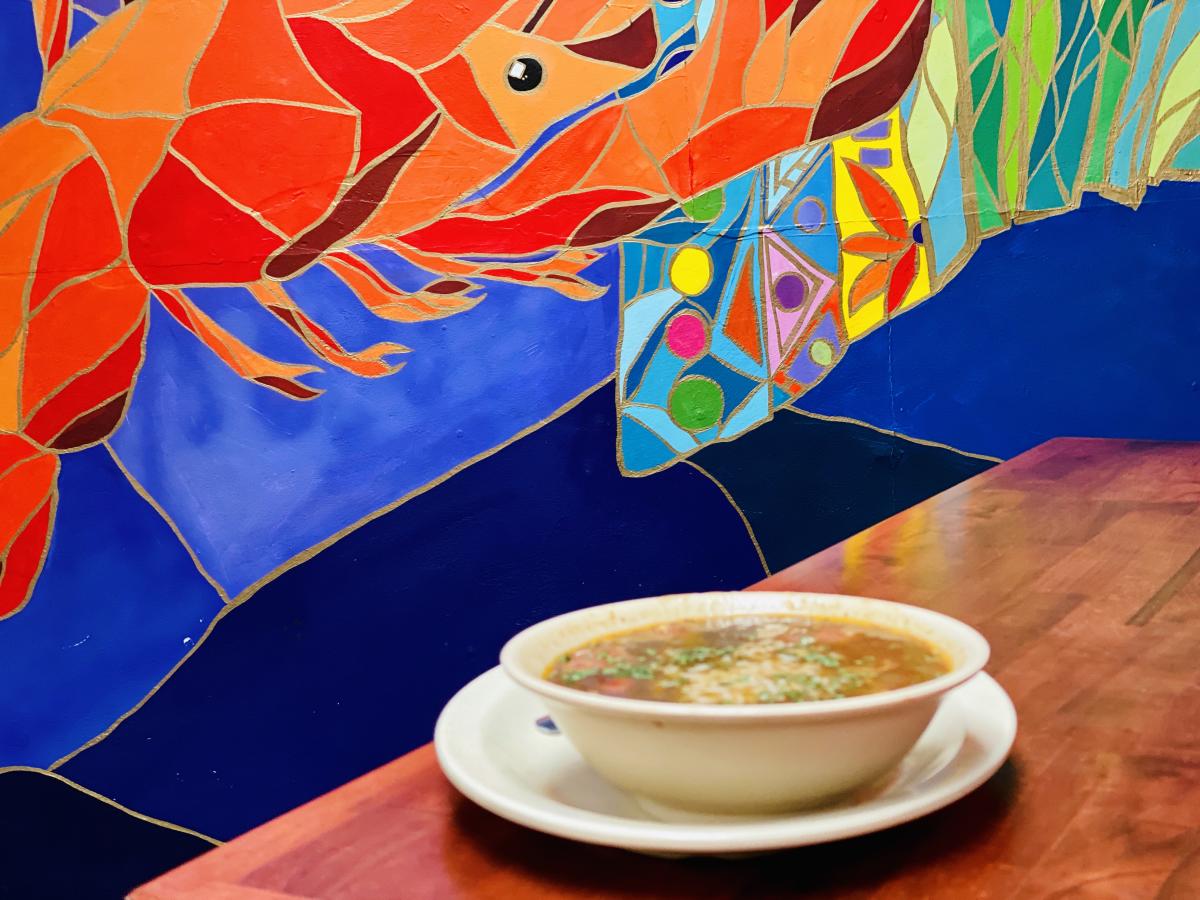 Bowl of gumbo on a table with a tile mural in the background at Crazy Cajun