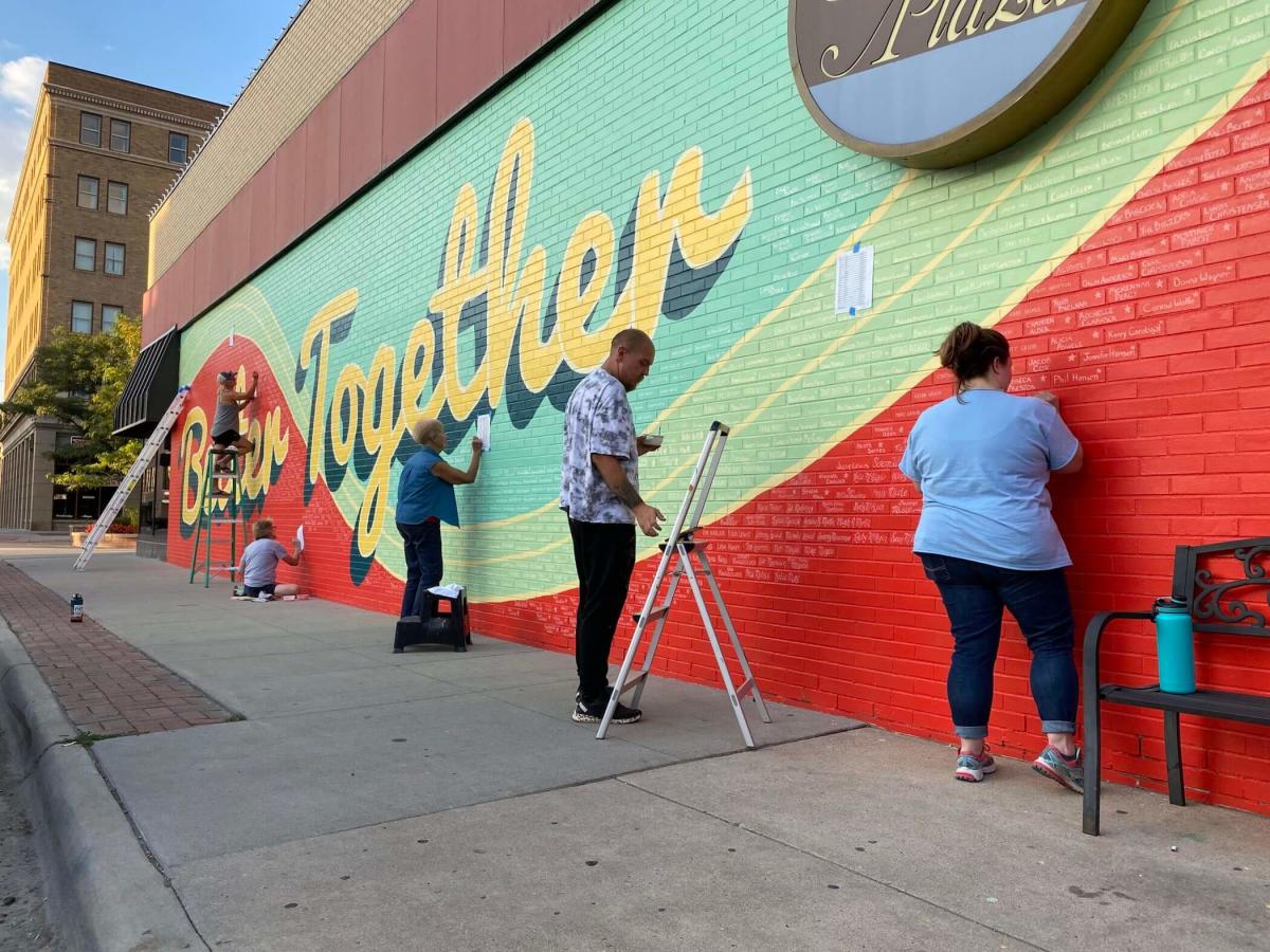 Artists within the community working on a mural in downtown Casper, WY that sends positive messages of being better together.