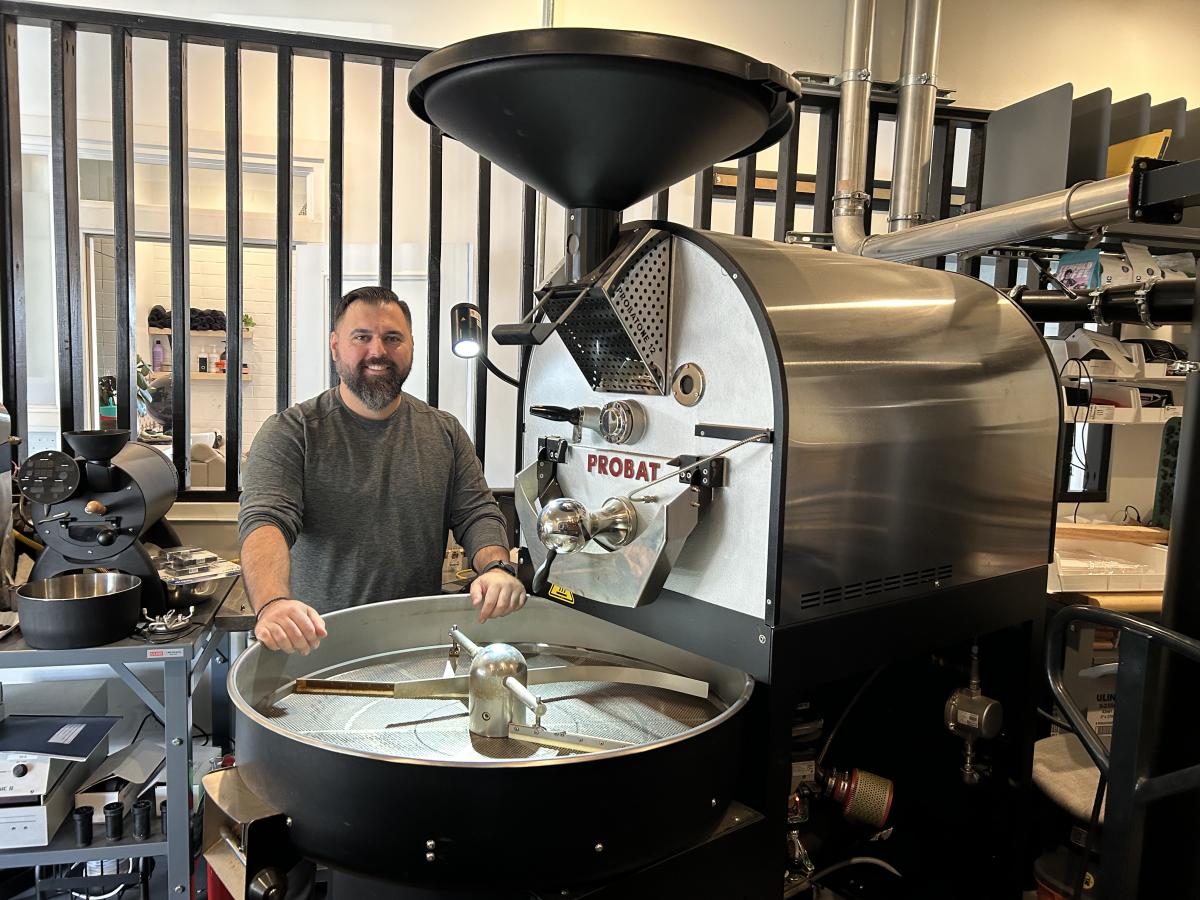 view of the coffee roaster at Aristocrat Coffee in Chandler AZ, with the owner, Paul Roupas, standing behind it