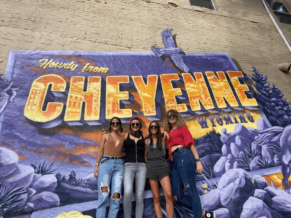 Group of friends at the iconic 'Howdy from Cheyenne' mural, a perfect selfie spot in Cheyenne.
