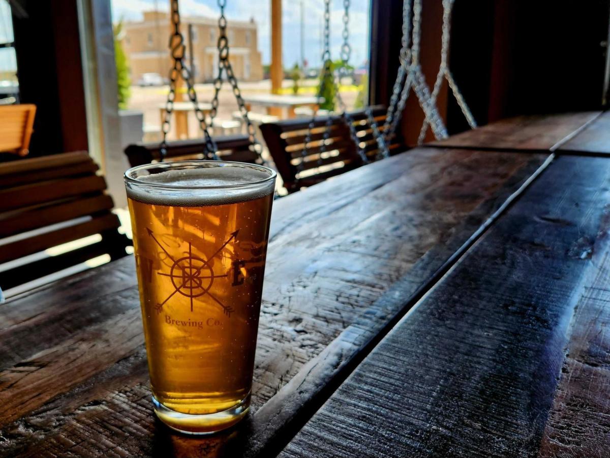 A glass of craft beer sitting on a rustic wooden table at Westby Edge Brewing, one of the best spots for craft drinks and local vibes, and a must-visit hidden gem and great for something to do in Cheyenne.