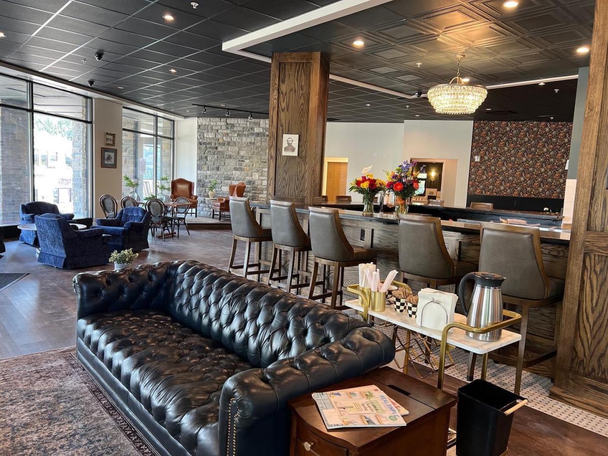 Inside Ft. Thomas Coffee where you can see a bar with chairs, a nice leather couch and additional table and chairs to the left.