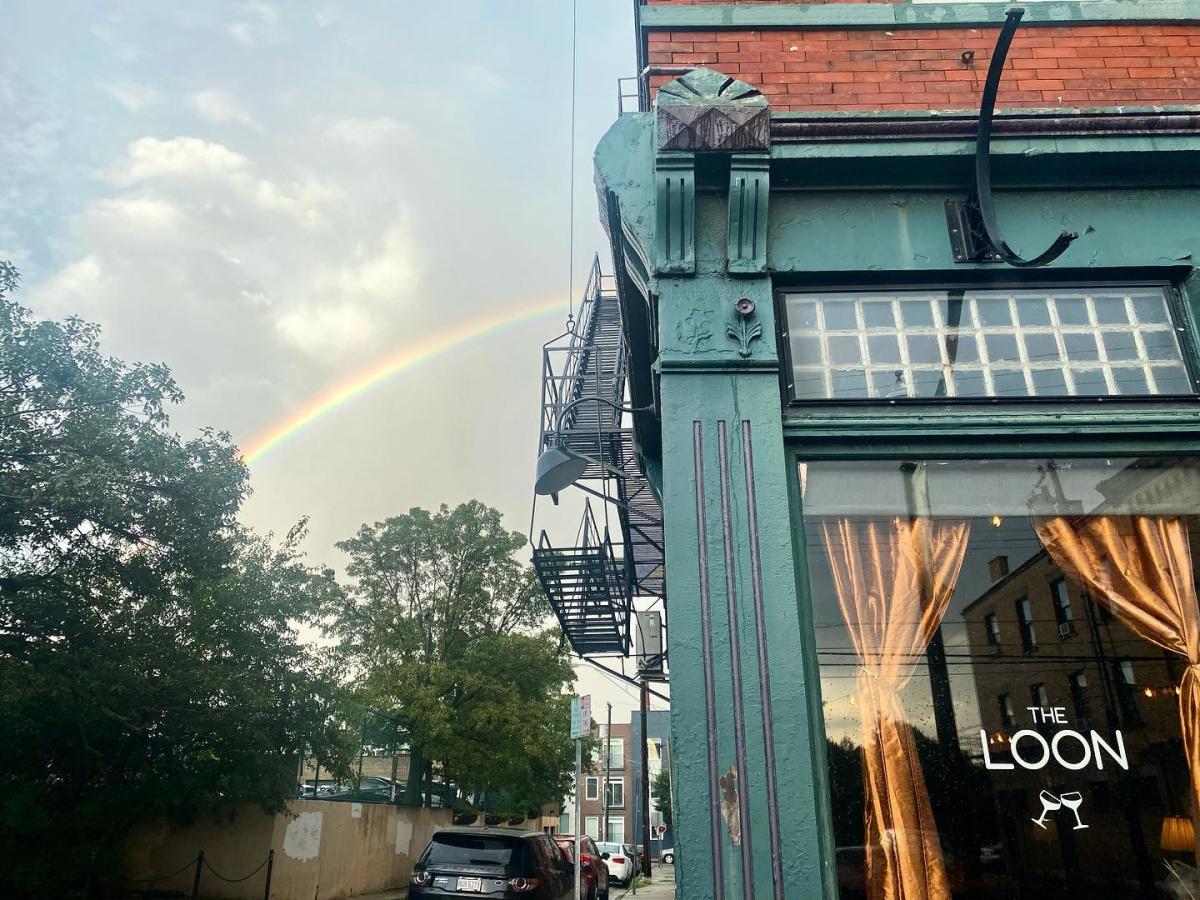 Exterior shot of the building with "The Loon" on the window and a rainbow in the sky next to the building.