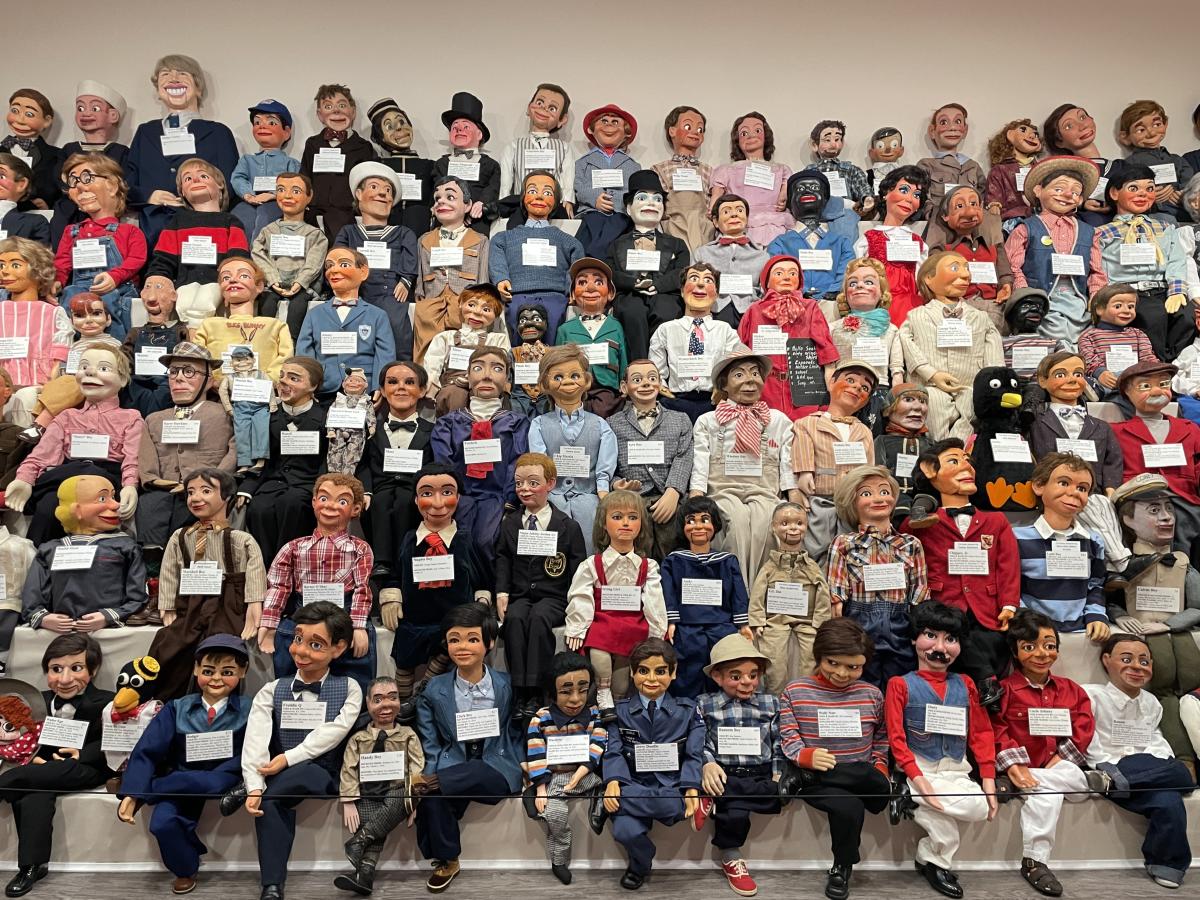 The image is of numerous dummies of all shapes and sizes lined on a bleacher.
