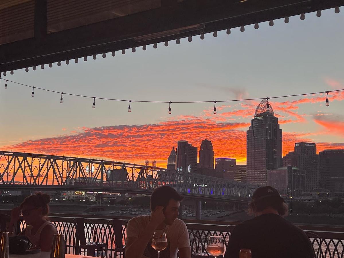 A beautiful orange sunset behind the Cincinnati Skyline with customers at the Beeline bar in Newport, Ky. in the foreground