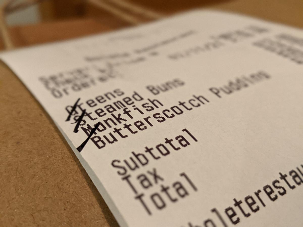 A takeout receipt from Bolete shows the customer ordered greens, steamed buns, monkfish, and butterscotch pudding.