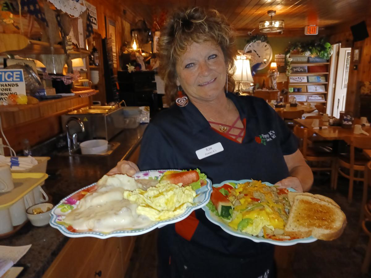 A lady holding two plates of breakfast at Pammy K's Cafe