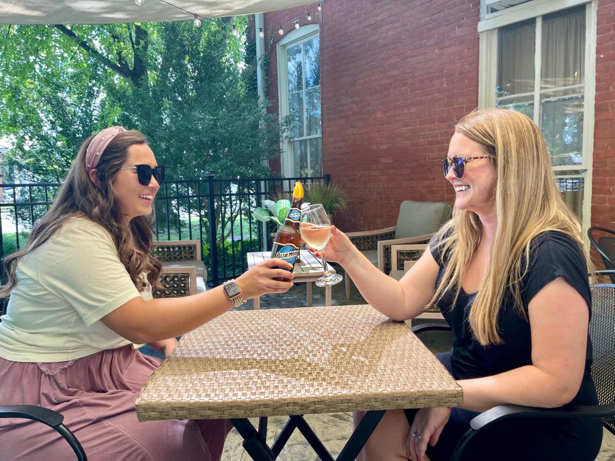 two women cheersing drinks on the back patio of back home