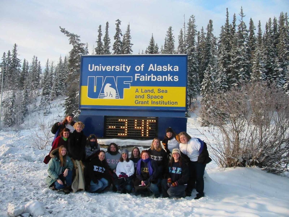 A group of people posing for a photo in front of the University of Alaska Fairbanks temperature sign. The temperature is -34°F.