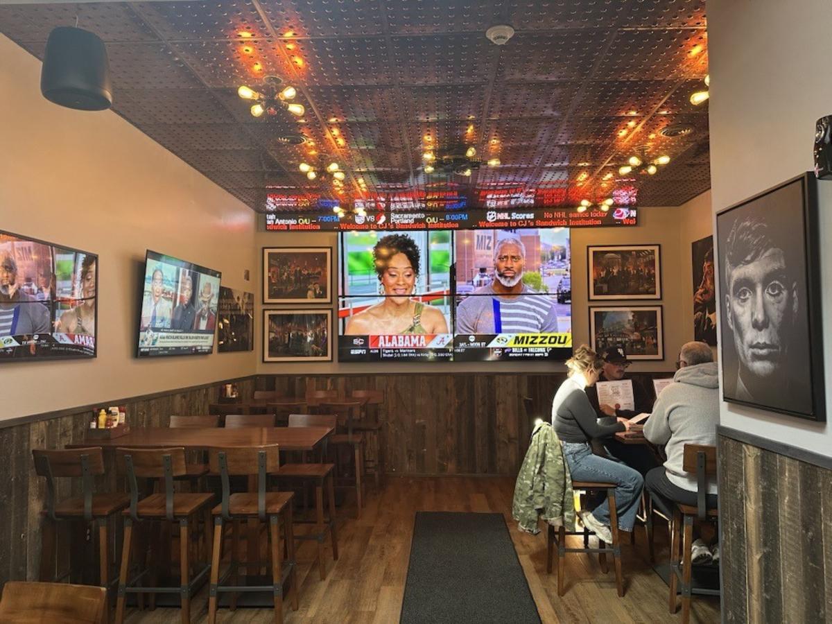 Interior of CJs Sandwich Institution in Geneva NY with dining tables and large television screens