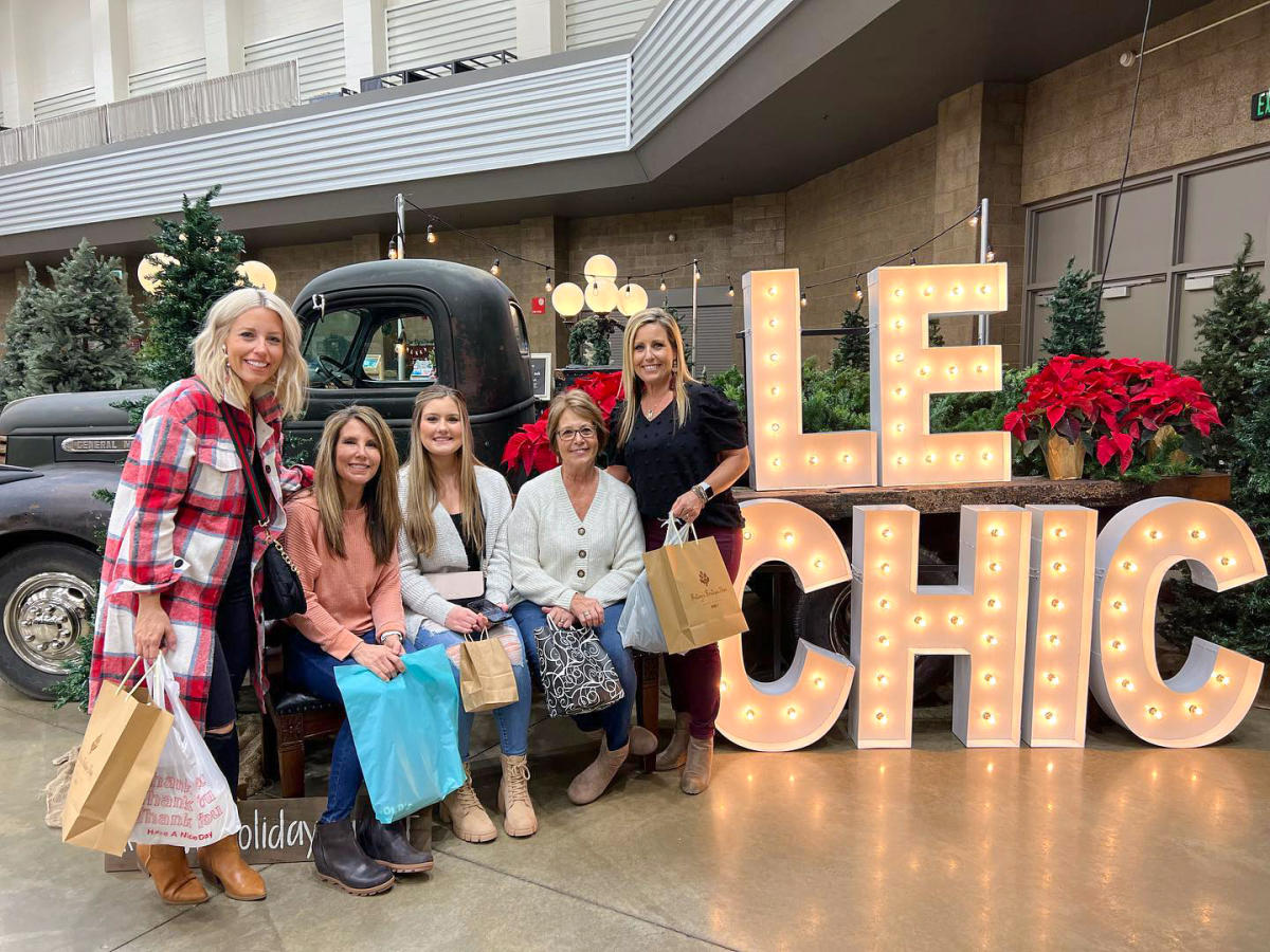 Five women at a holiday shopping event posing to have their picture taken