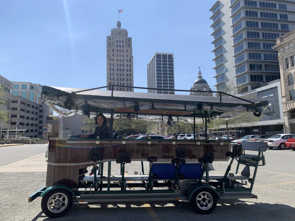 Pedal City Pub Bike is parked in a parking lot with a driver smiling at the camera