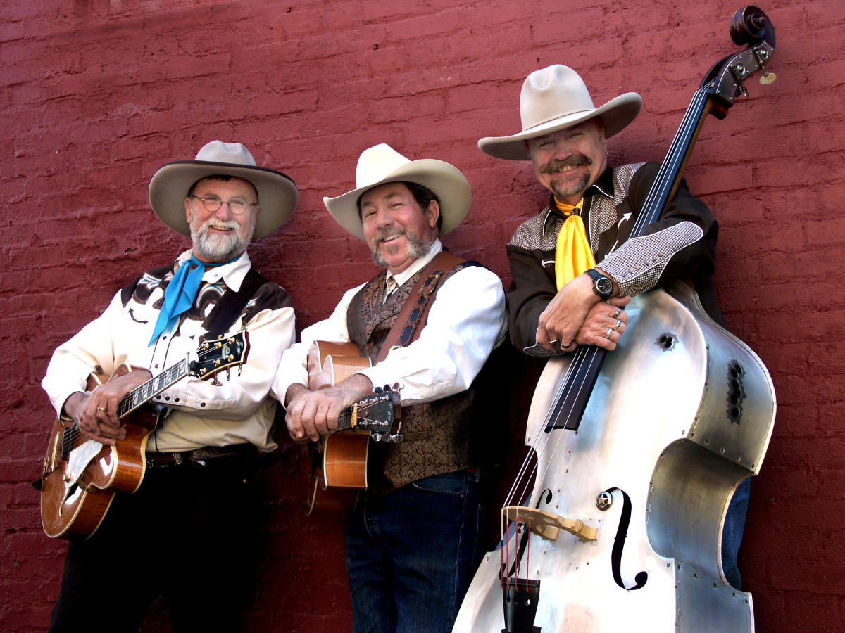 The three band members of 3 Trails West wearing traditional western clothing and cowboy hats with guitars and a stand up bass
