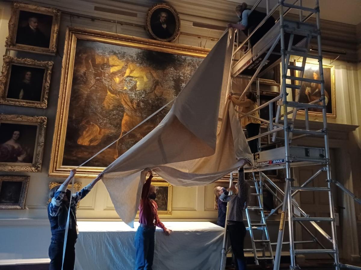 people using sheets to cover an historic painting