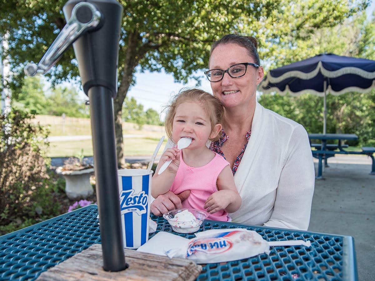 A woman and a little girl eating Zesto Ice Cream outside in Angola.