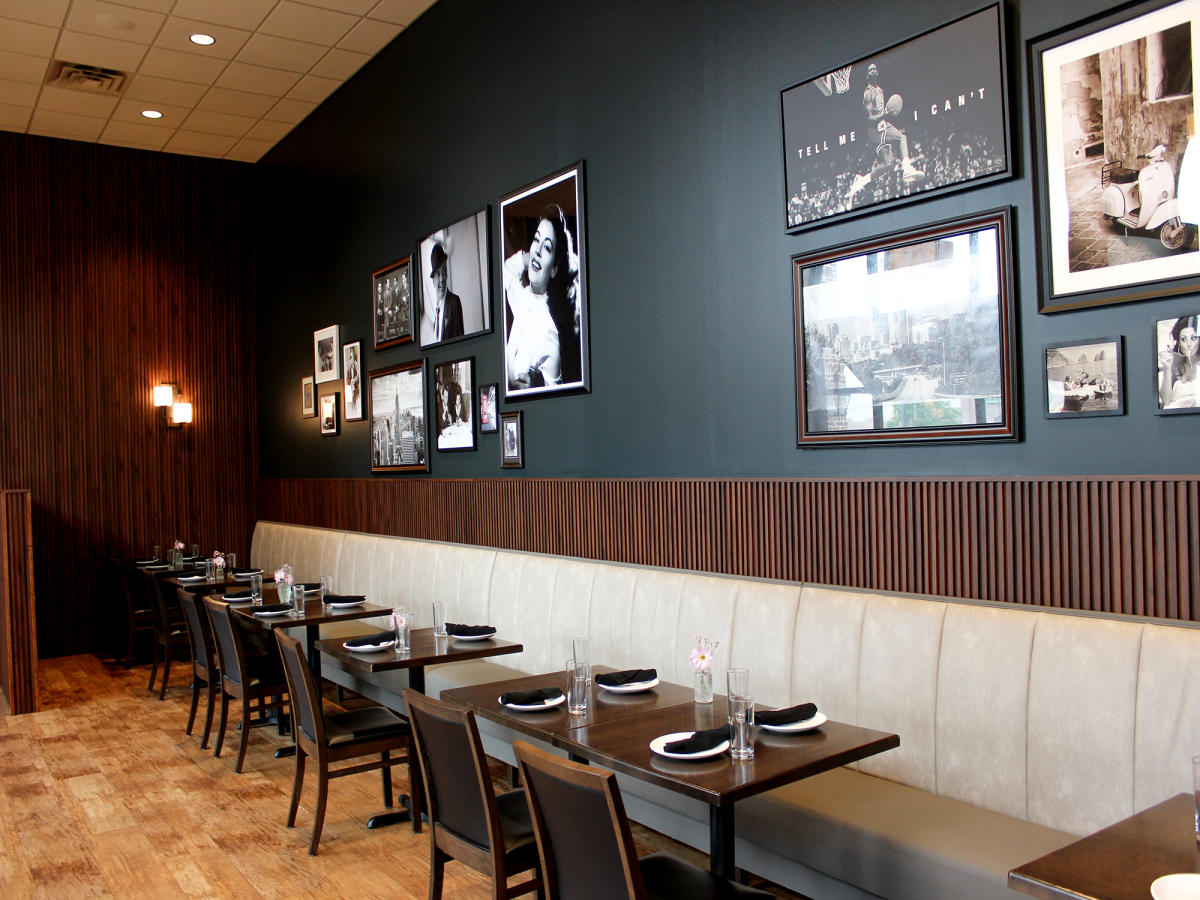 A row of tables with a photo gallery on the wall.