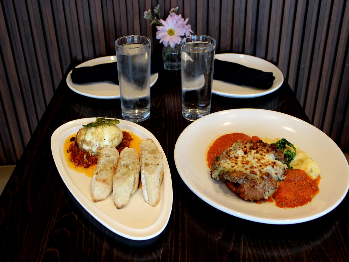 Two Italian dishes on a table with two glasses of water.