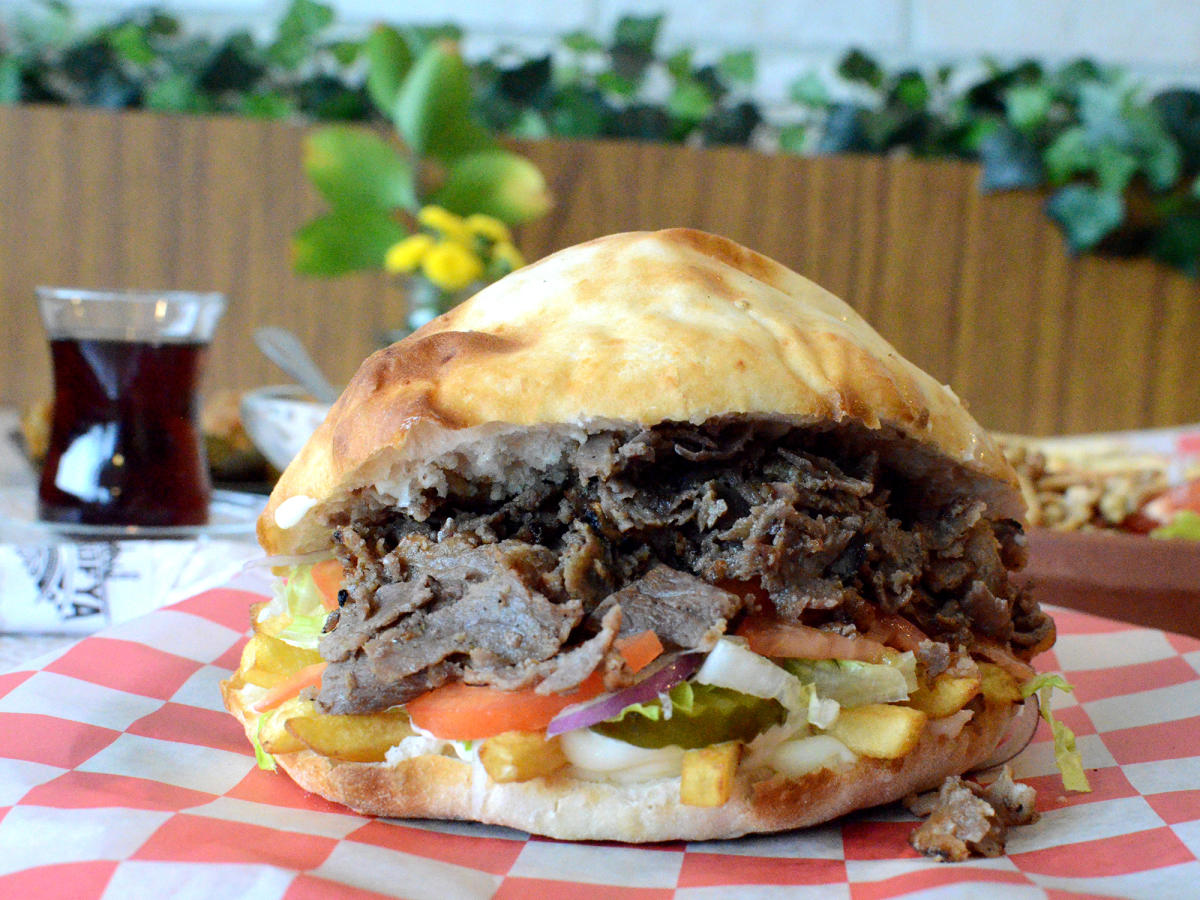 A sandwich from Ayasofya Turkish Restaurant sits on a red and white plaid napkin.