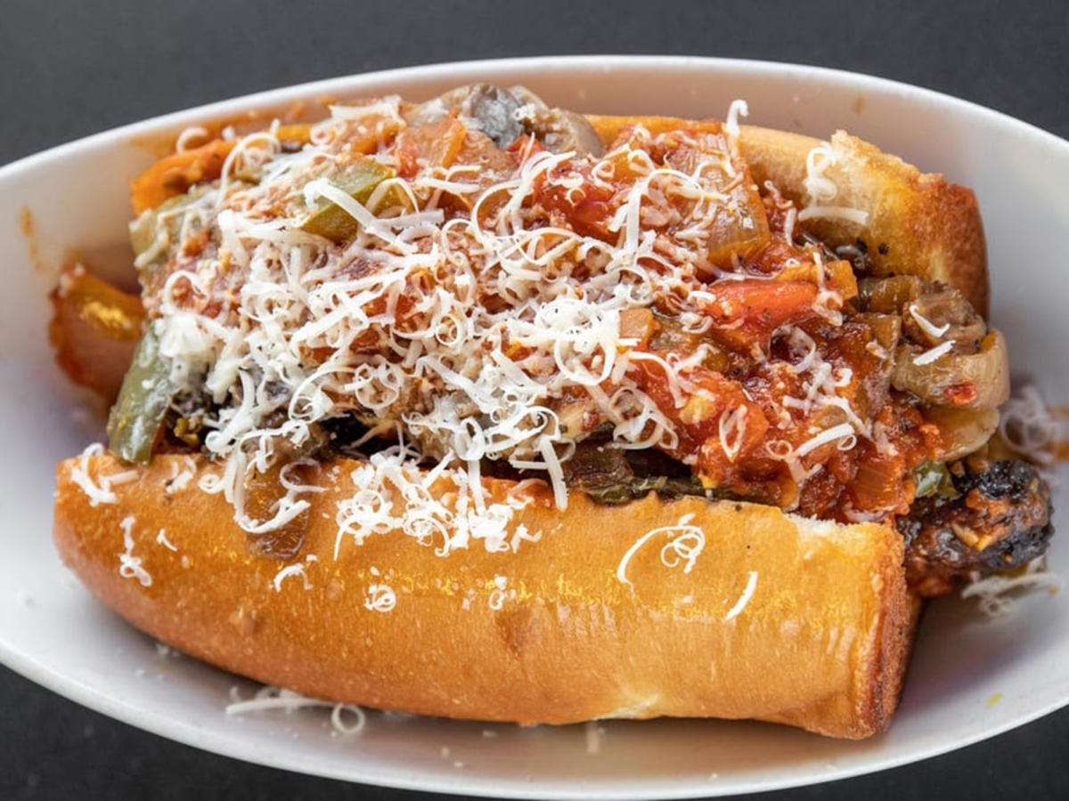An Italian sausage is covered in shredded mozzerella and red sauce, all in a toasted bun, at Ray Ray's Italian Beef & Sausage