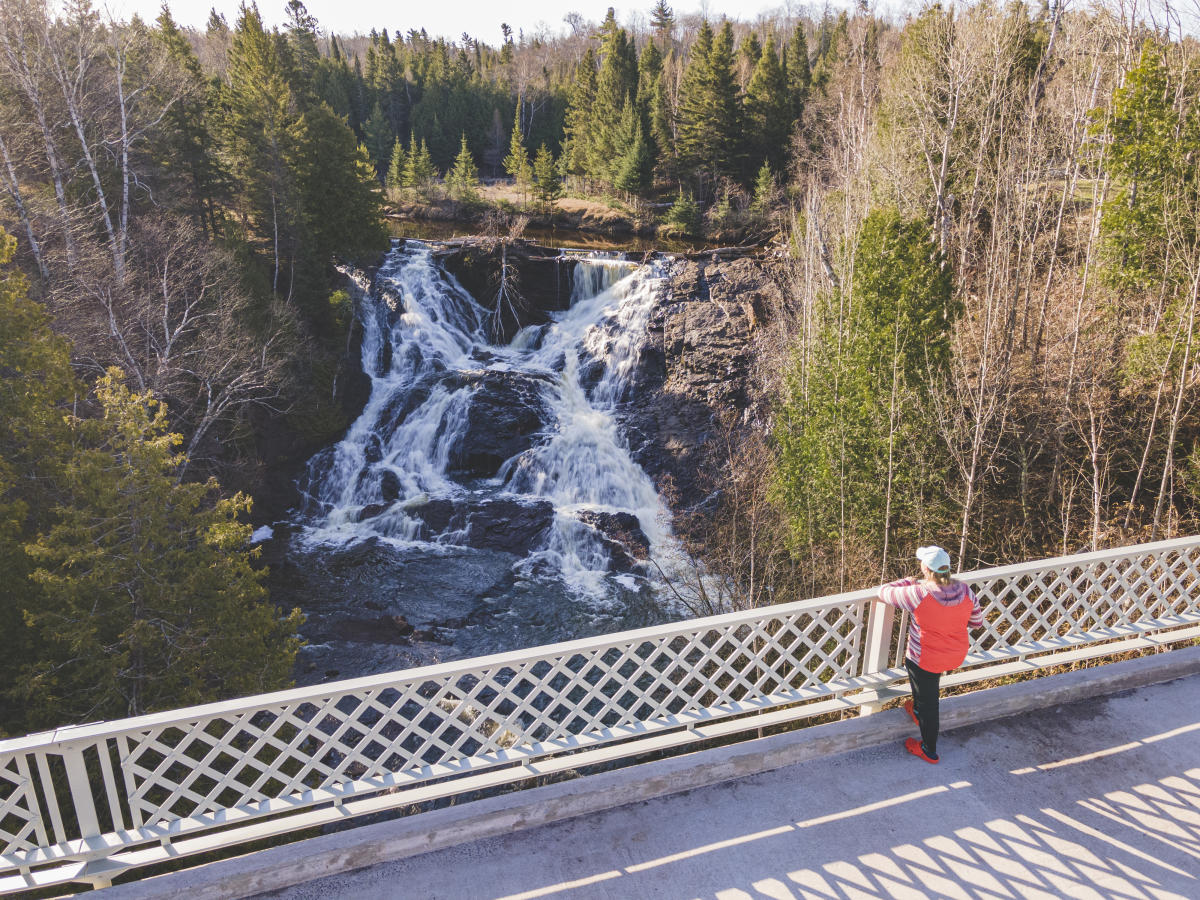 Person looks at Eagle River Falls from bridge.