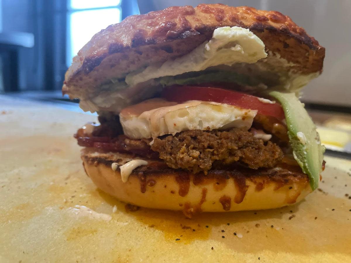 Asiago bagel piled high with hamburger patty and toppings