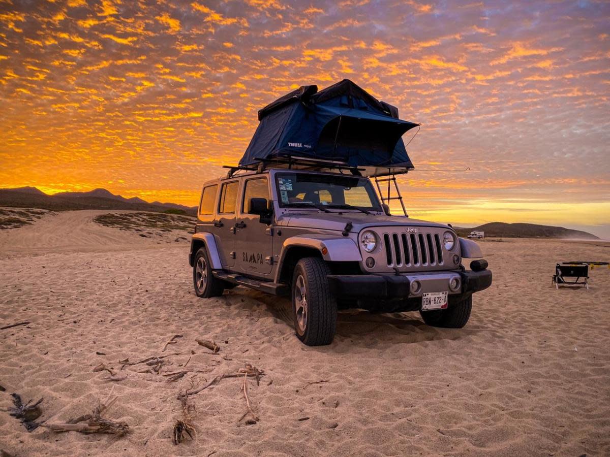 Jeep out in the desert with a tent mounted to the top of the Jeep