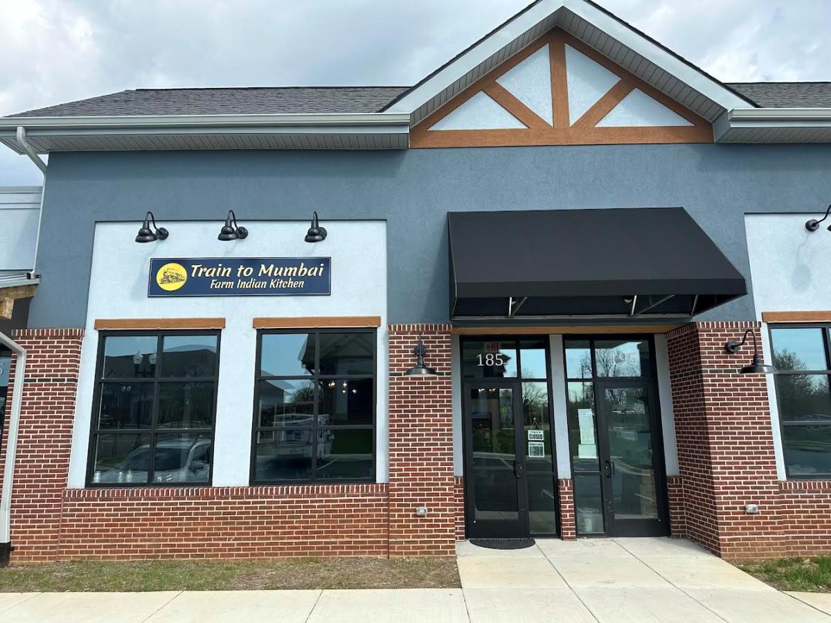 Exterior of Train to Mumbai Farm Indian Kitchen in Lovettsville, Loudoun County, with brick facade and black awning entrance